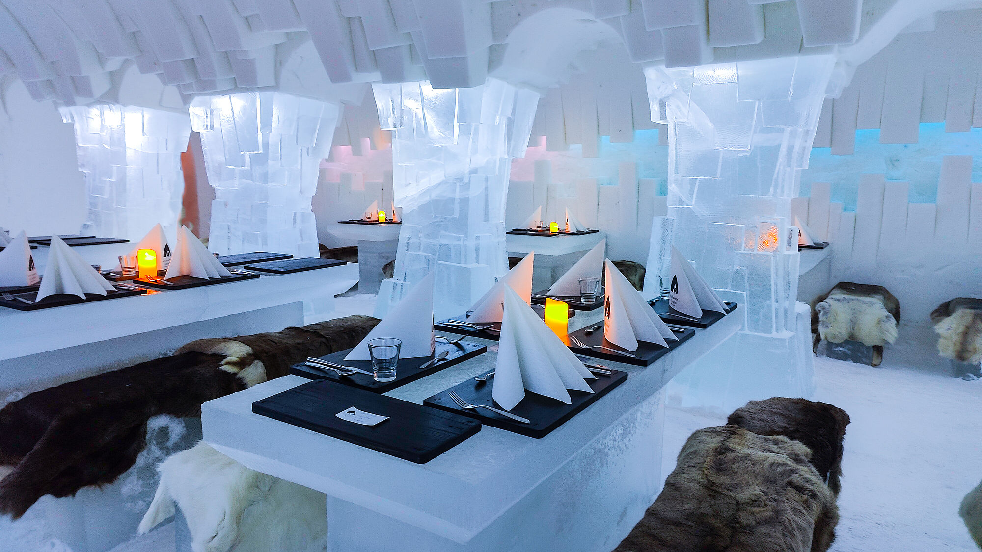 Katettuja pöytiä Arctic SnowHotelin jääravintolassa.