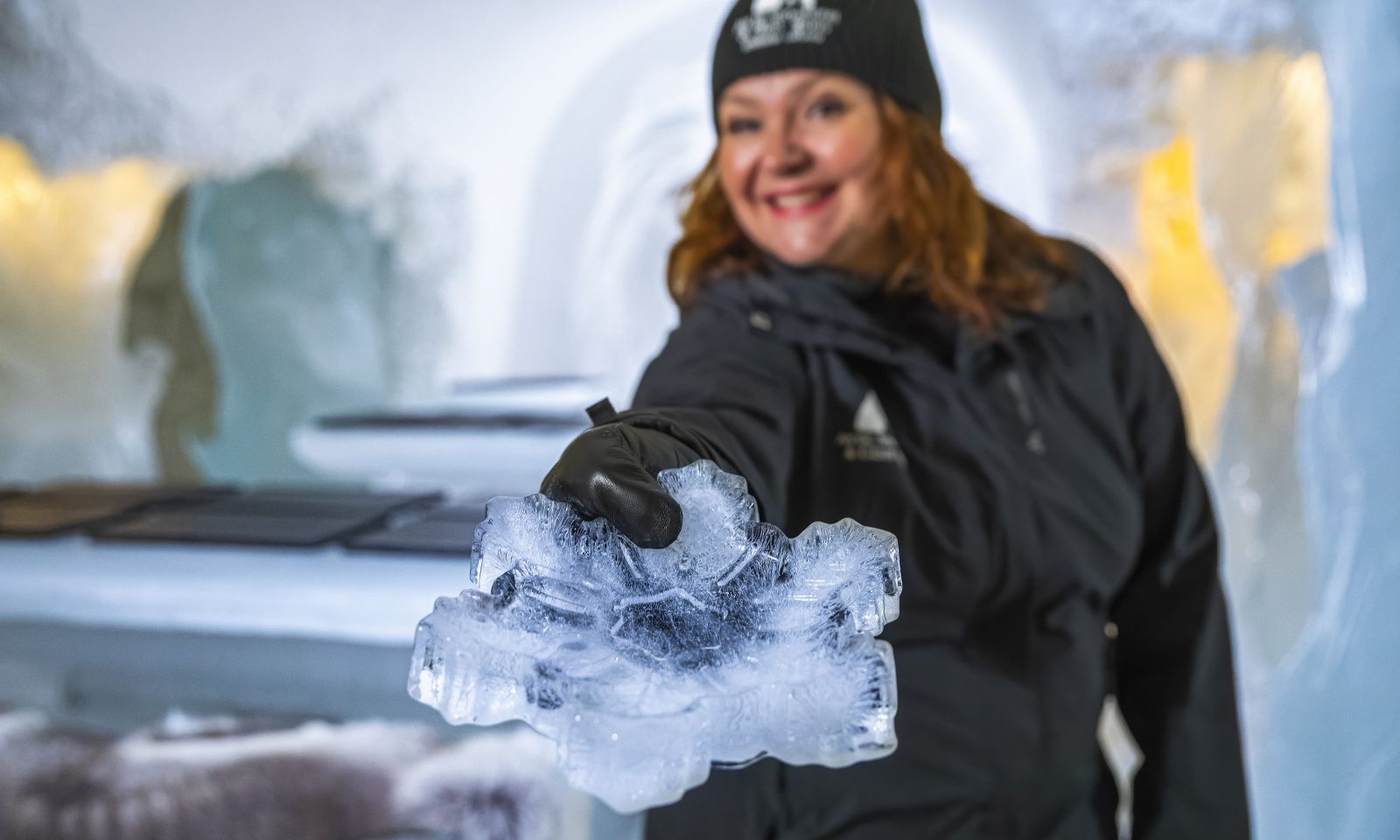 Tarjoilija ojentaa jäästä valmistettua lumihiutaleen mallista tarjouilulautasta.