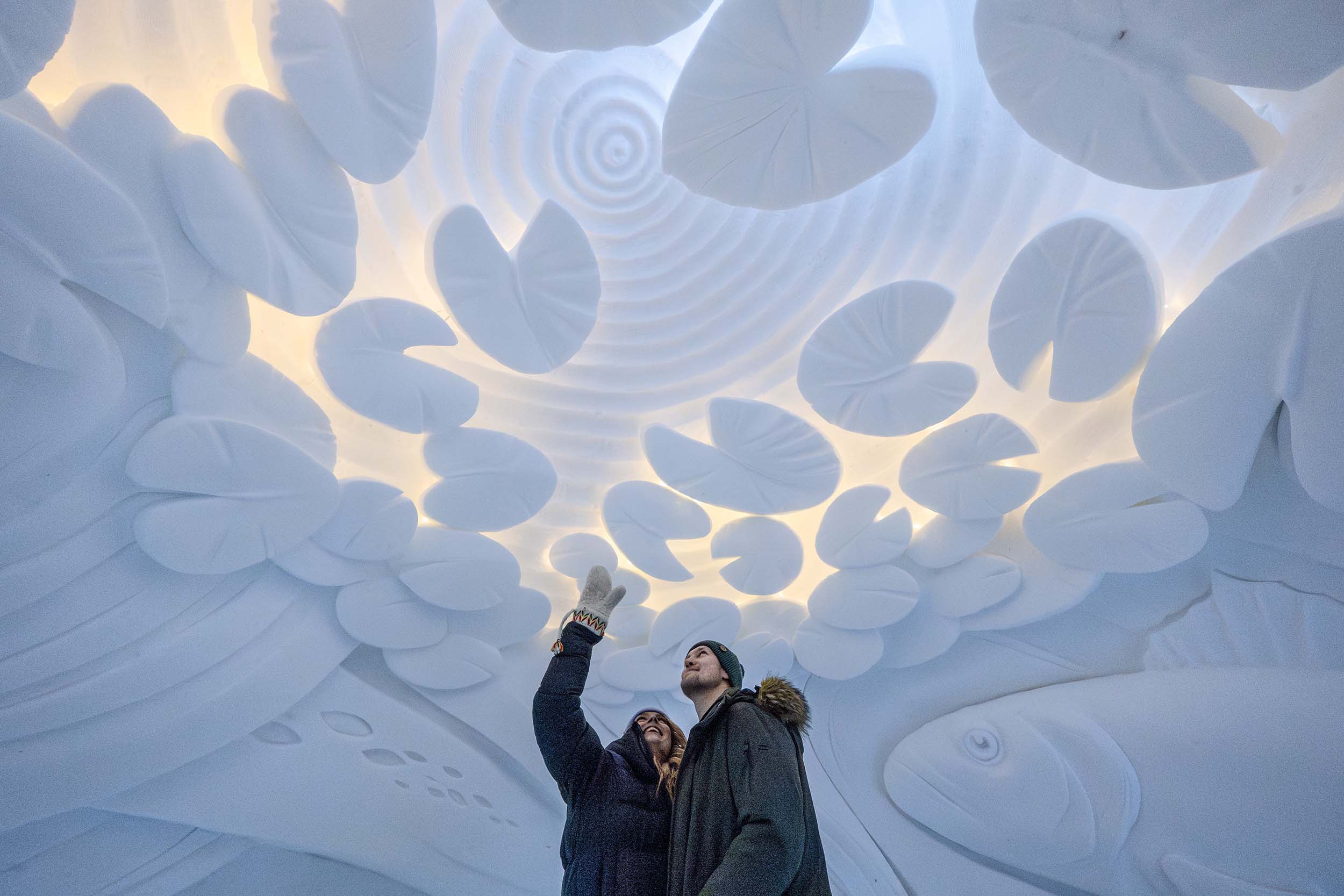 Two visitors admiring the snow art in the Arctic SnowHotel