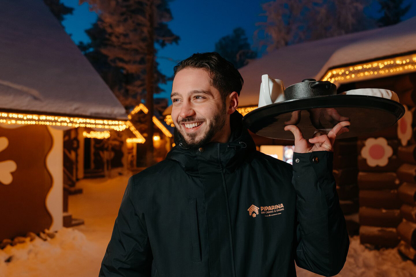 A waiter smiling in front of Piparina Day Cabins & Dining.
