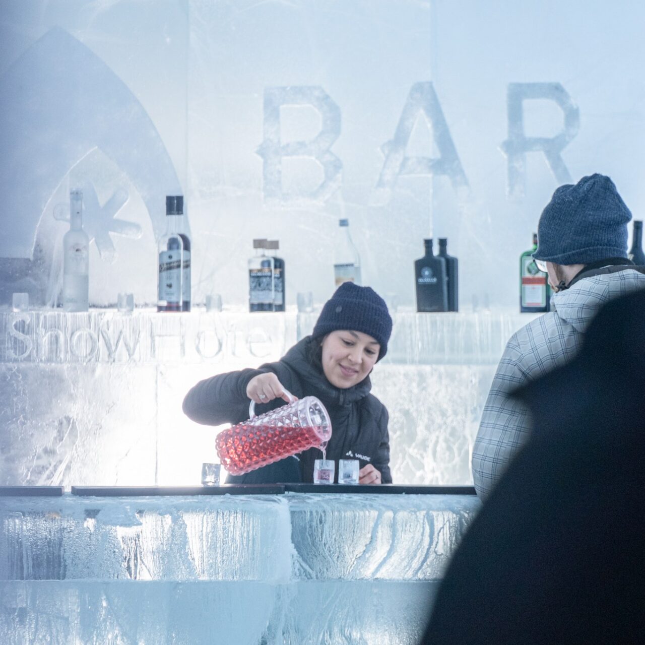 Tarjoilija kaataa juomaa jäälasiin Jääbaarissa Arctic Snowhotelissa.