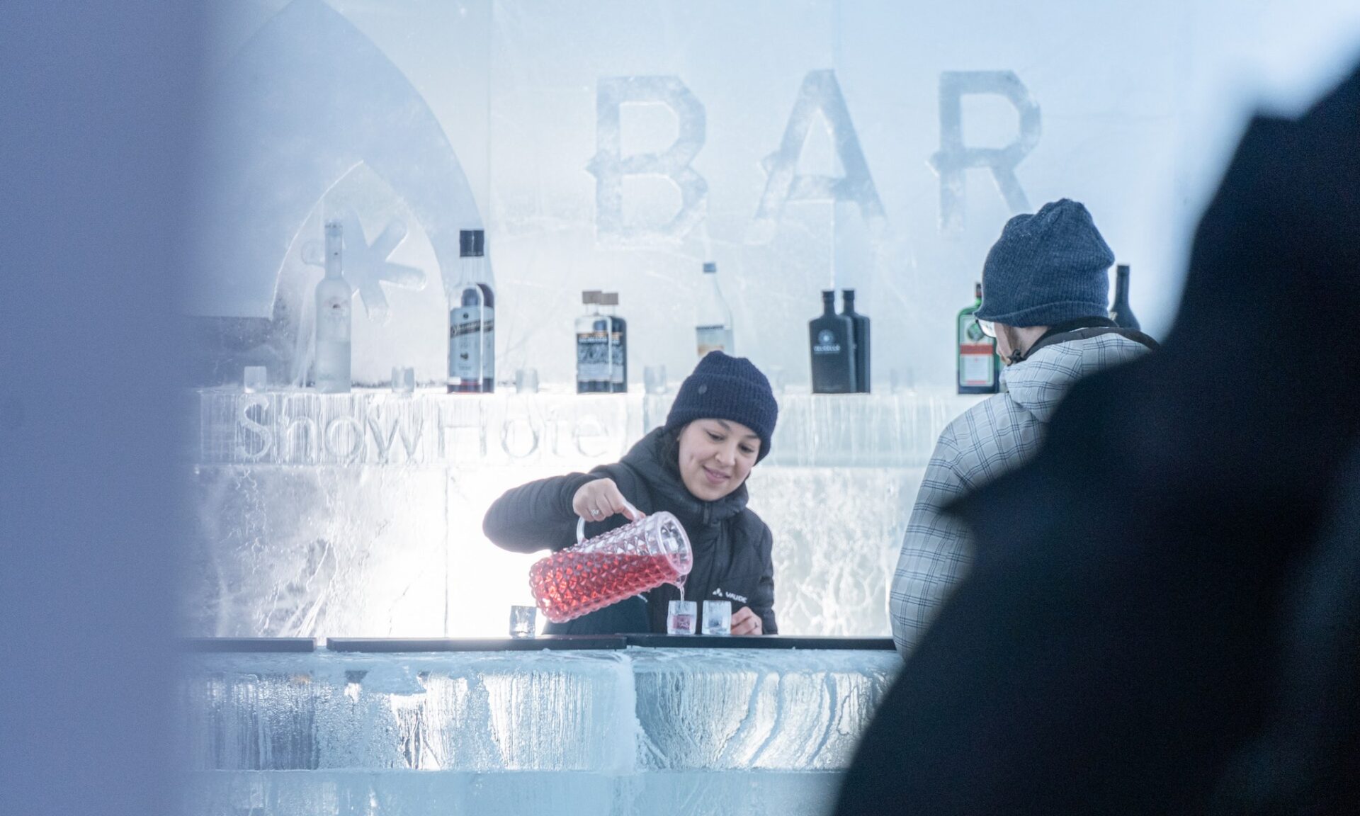 Tarjoilija kaataa juomaa jäälasiin Jääbaarissa Arctic Snowhotelissa.