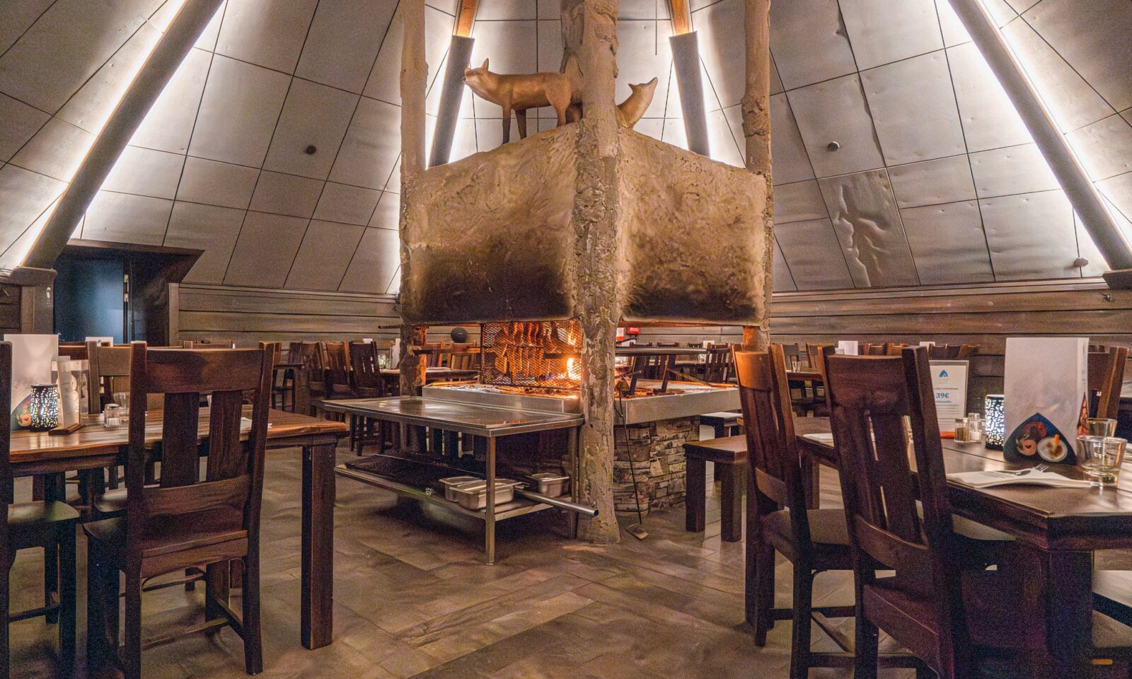 Interior of Kota Restaurant with a central fireplace at Arctic SnowHotel & Glass Igloos.