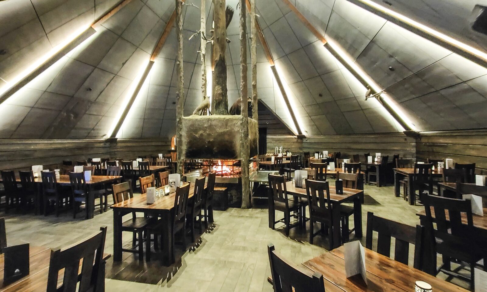 Spacious Kota Restaurant with a central fireplace at Arctic SnowHotel & Glass Igloos.