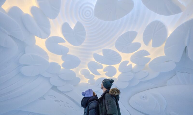 Visitors exploring snow and ice art inside Arctic SnowHotel.